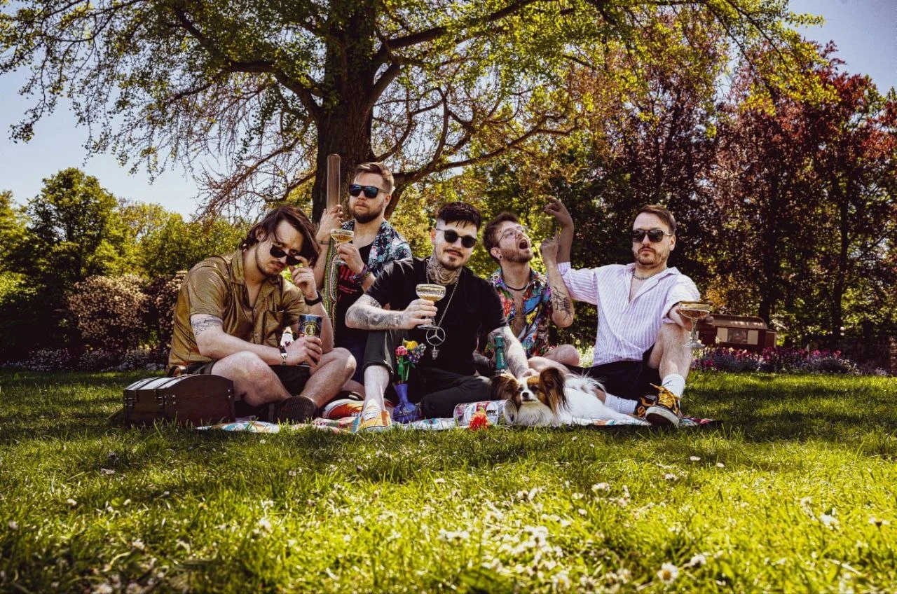The current And Phobos Falls lineup sitting together on a picnic blanket in a park